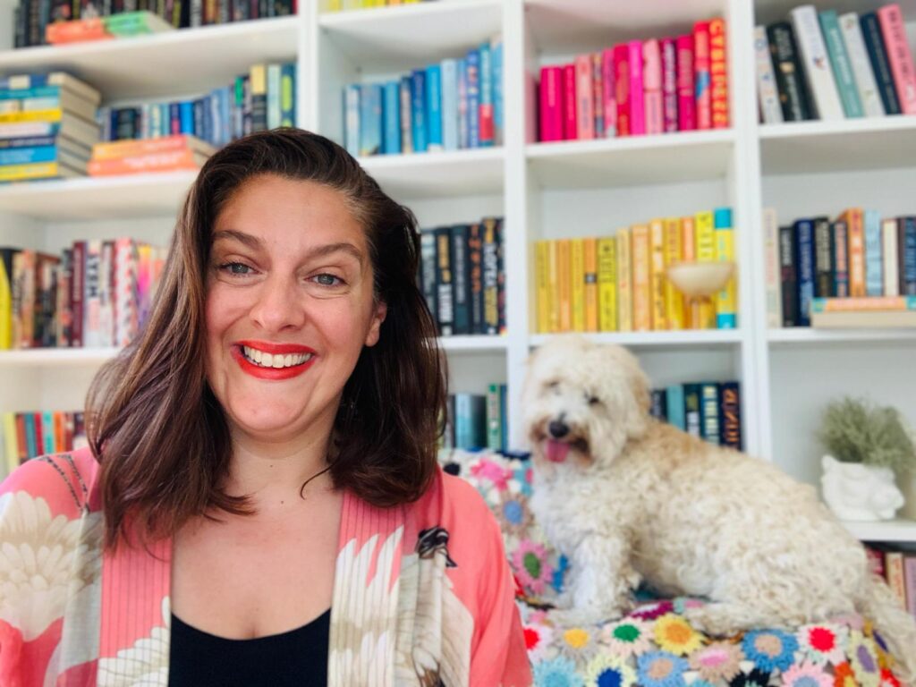 Helen Gambarota smiling at the camera with her dog Roddy sitting behind her